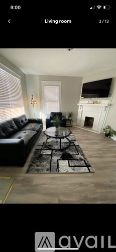A living room with a black couch and a rug.