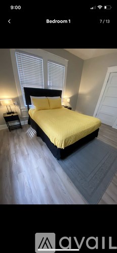 A bedroom with a bed, nightstand, and window with blinds.
