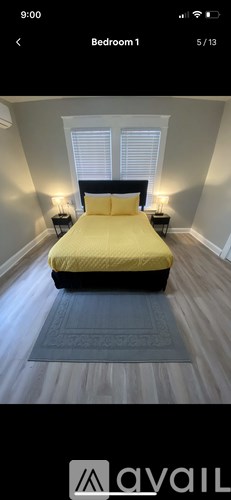 A bedroom with a bed, two lamps, and a window.