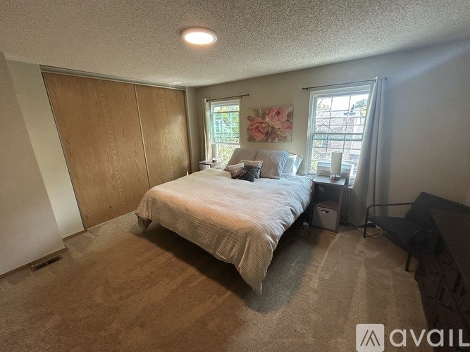 A bedroom with a bed, nightstand, and chair.