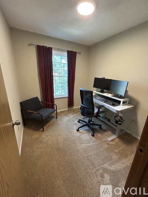 A room with a desk, chair, and a window with red curtains.
