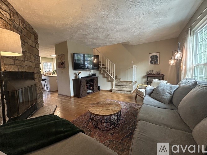 A living room with a stone fireplace and a flat screen TV mounted on the wall.