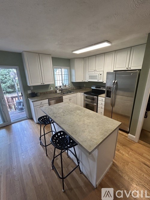 A kitchen with a white island and stools.