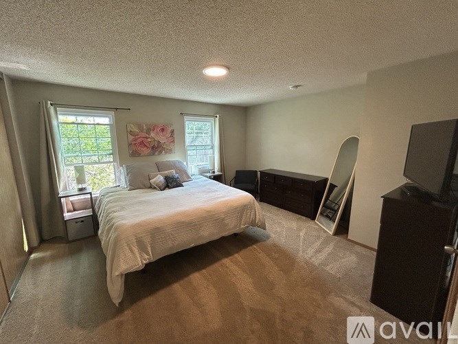A bedroom with a bed, dresser, and window.