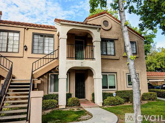 A two-story house with a red tile roof and a balcony on the second floor.