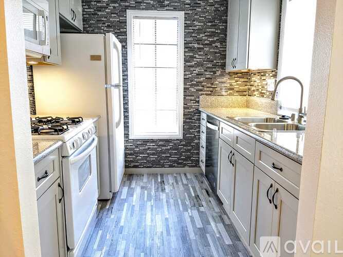 A kitchen with a stove, sink, and refrigerator.