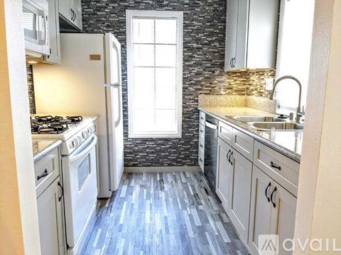 A kitchen with a stove, sink, and refrigerator.