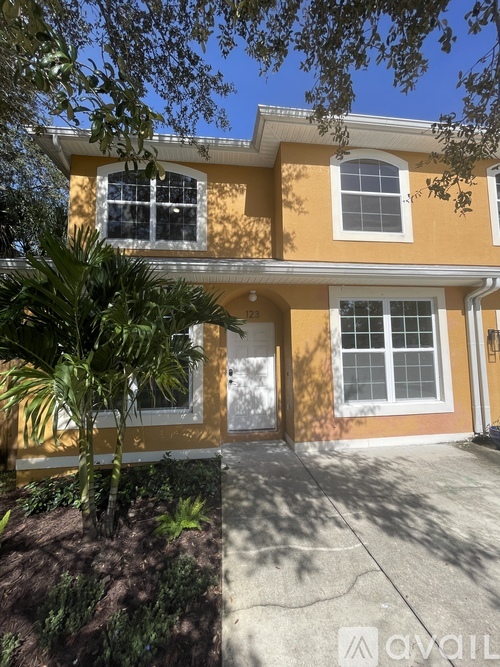 A yellow house with a white door and windows.