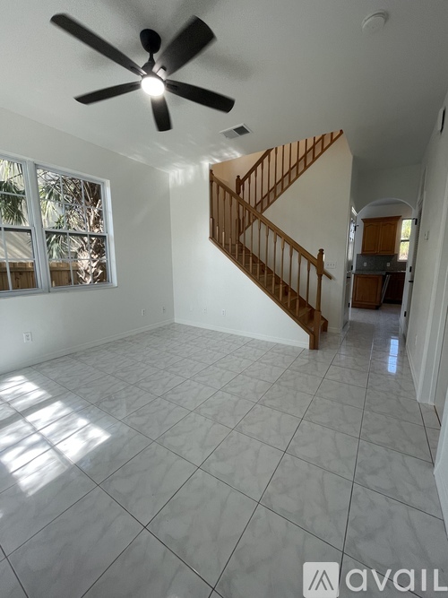 A spacious room with a ceiling fan and a staircase.