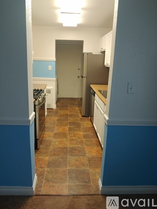 A kitchen with a tile floor and a refrigerator.