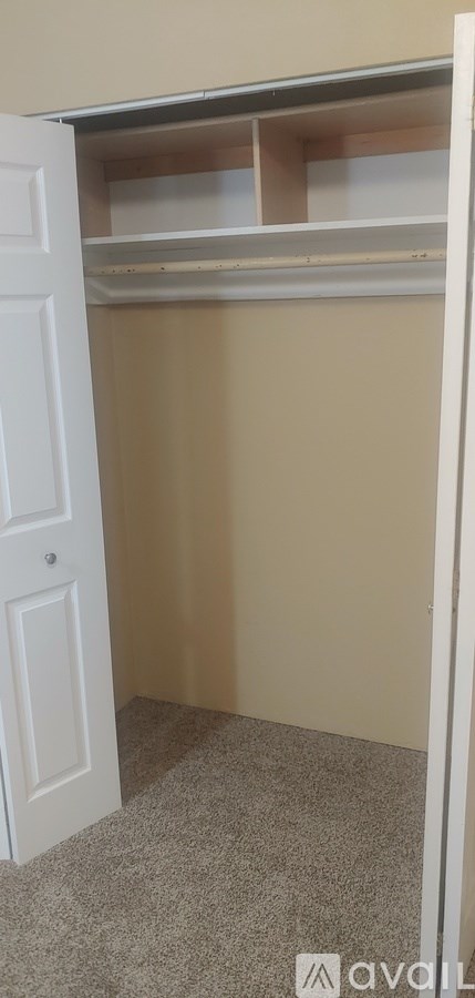 A white door is open to a room with a white shelf.