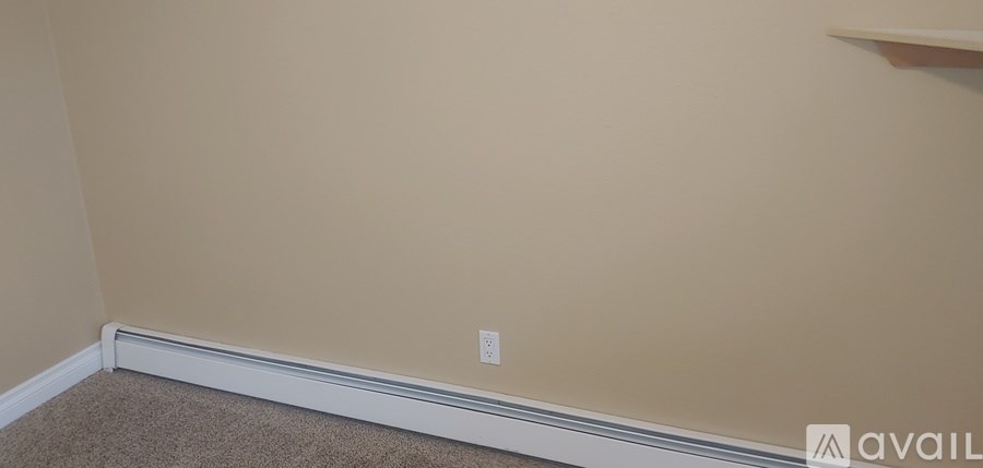 A room with a beige wall and a white baseboard.
