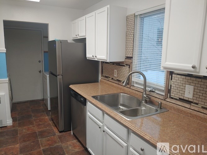 A kitchen with a sink, refrigerator, and cabinets.