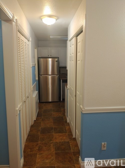 A long hallway with a refrigerator at the end.