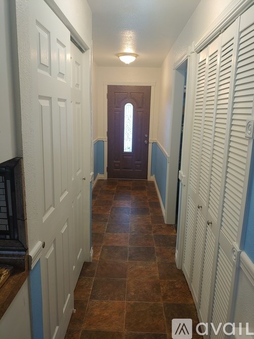 A hallway with white doors and brown tile flooring.