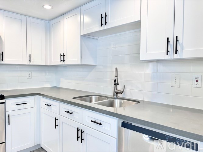 A kitchen with white cabinets and a stainless steel sink.