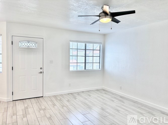 A room with a ceiling fan and a window with blinds.