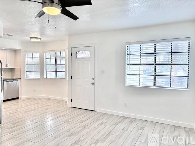 A spacious room with a ceiling fan and a window with blinds.