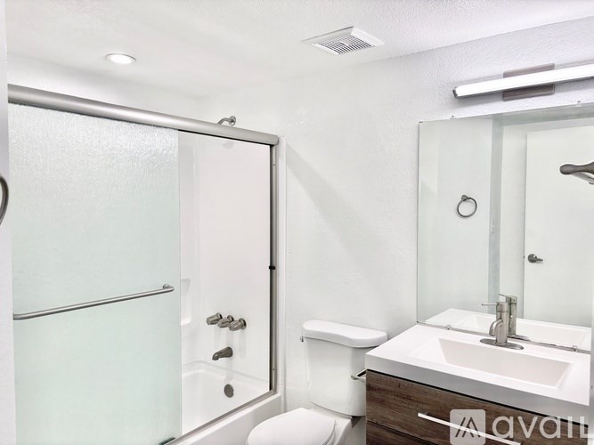 A white bathroom with a toilet, sink, and shower.