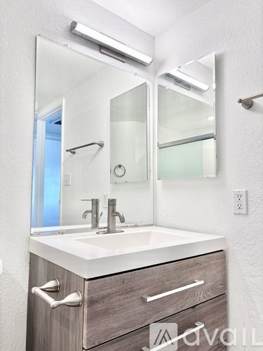A bathroom with a sink, mirror, and lighting fixture.