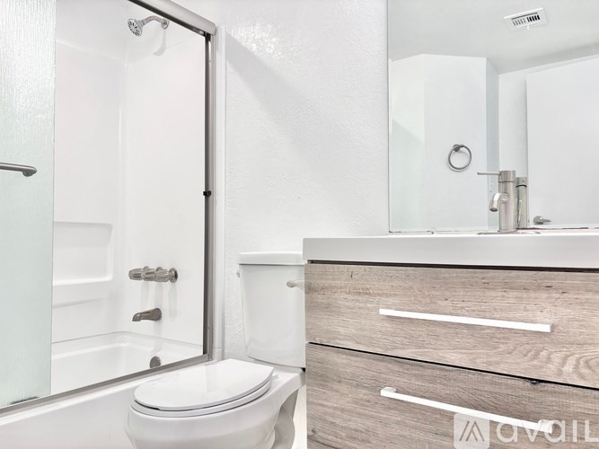 A white toilet sits next to a walk-in shower in a bathroom.