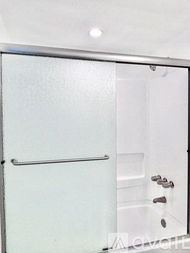 A glass shower door with a handle and a glass door.
