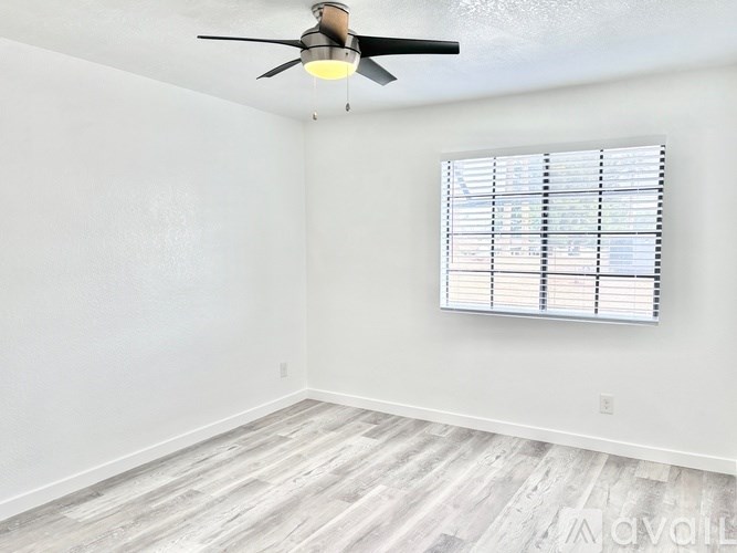 A room with a ceiling fan and a window with blinds.