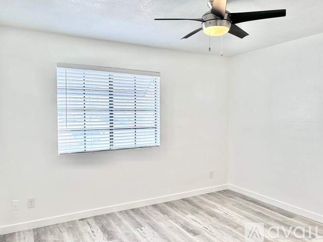 A room with a ceiling fan and a window with blinds.