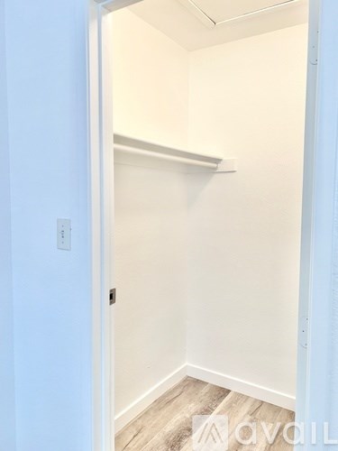 A white door is open to a room with a white wall and a shelf.