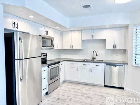 A modern kitchen with white cabinets and stainless steel appliances.