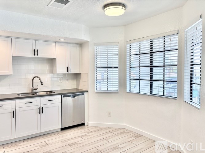 A kitchen with white cabinets and a black countertop.