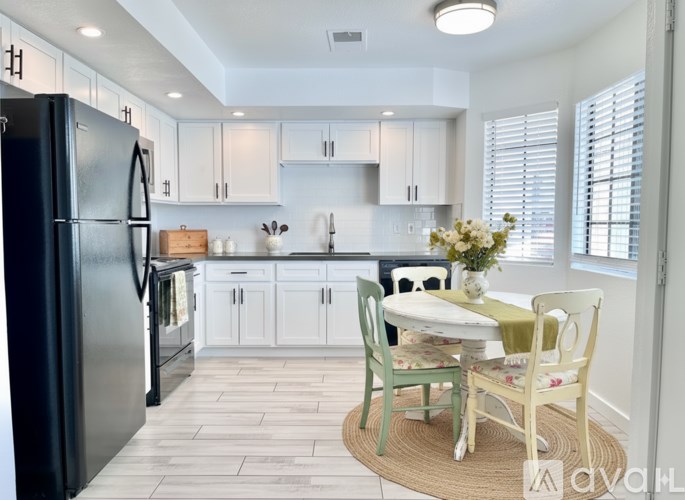 A kitchen with a black refrigerator and white cabinets.