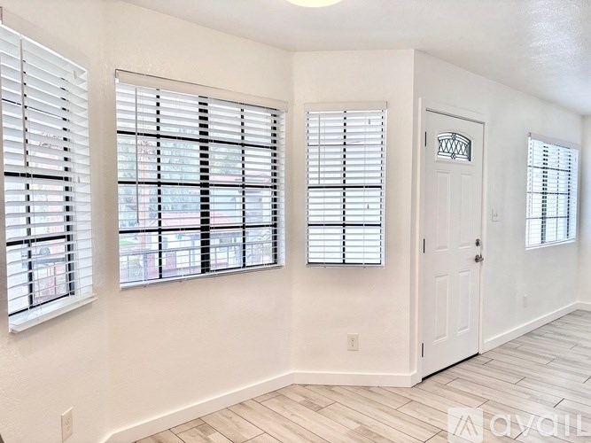 A room with white walls and a white door with a glass window on the left side.