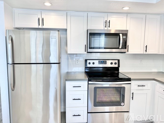 A kitchen with white cabinets and a stainless steel refrigerator.