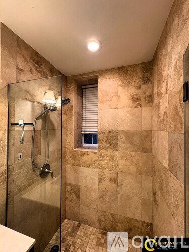 A bathroom with a tiled shower and a window.