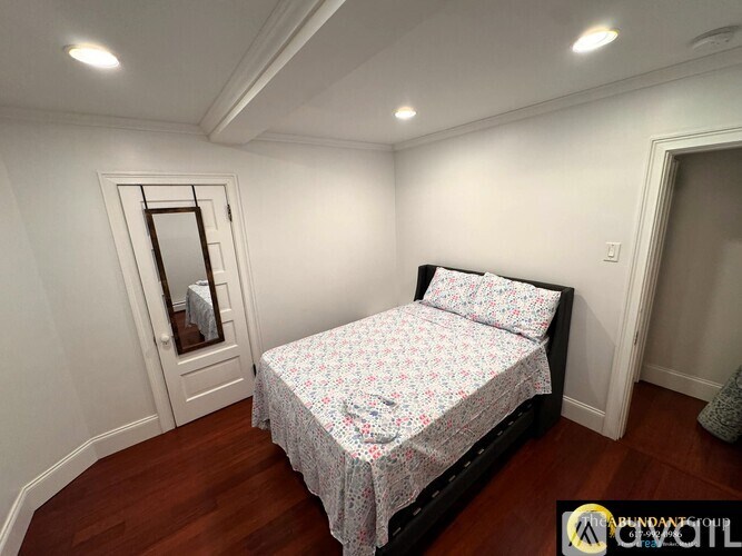 A bedroom with a bed, a mirror, and a window.