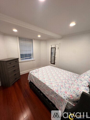 A bedroom with a bed, dresser, and window.