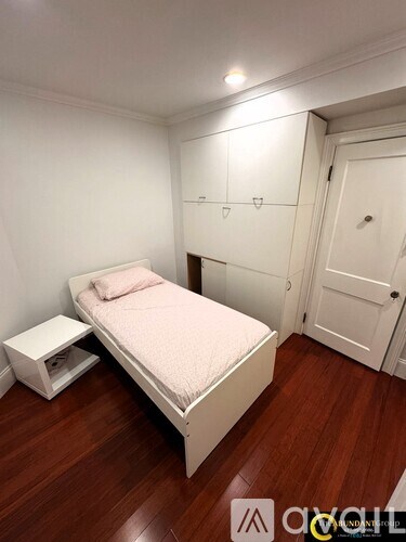 A bedroom with a bed, a nightstand, and a door.