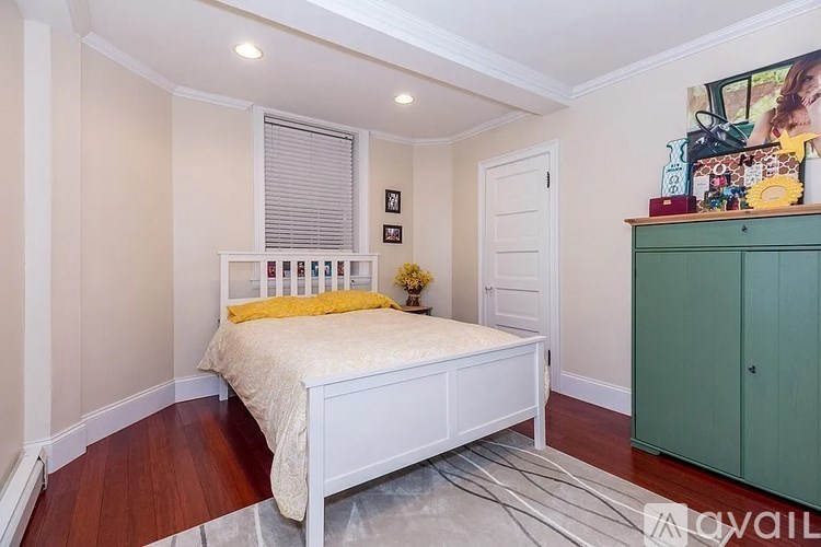 A bedroom with a white bed and a green cabinet.