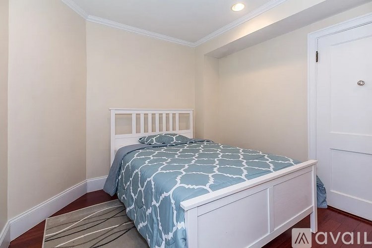 A bedroom with a bed and a striped rug.