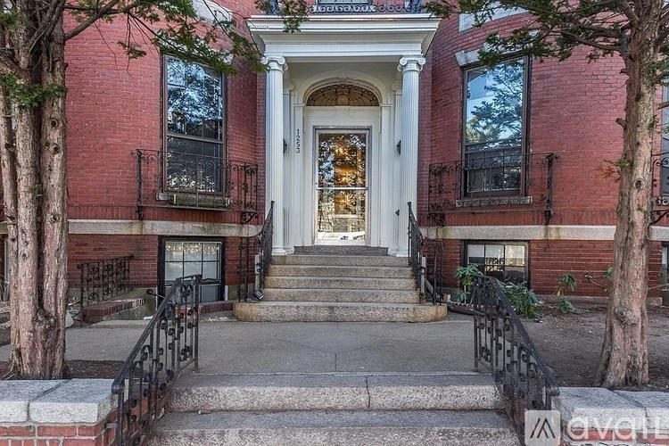A red brick building with a white door and steps leading up to it.
