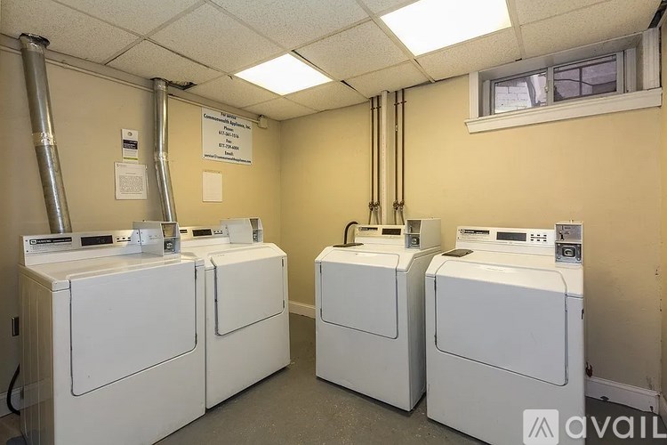 Three white washing machines in a laundry room.