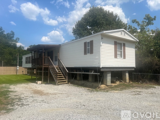 A mobile home with a deck and stairs leading to the front door.