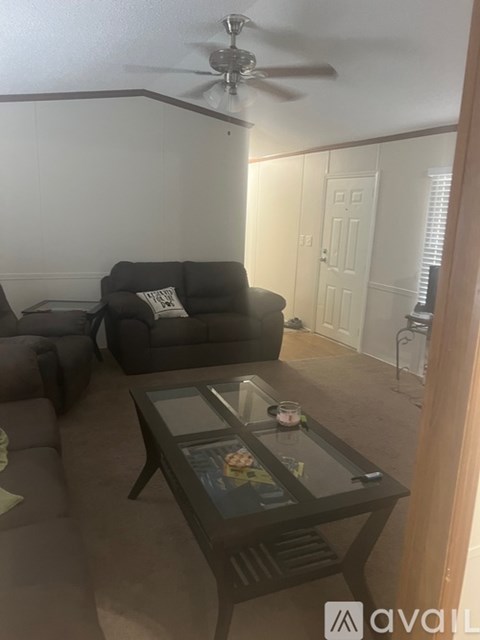 A living room with a grey couch and a glass coffee table.