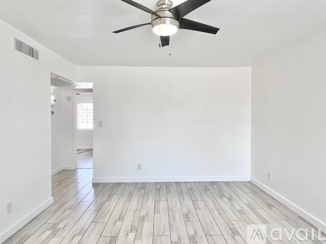 A room with a ceiling fan and wooden flooring.