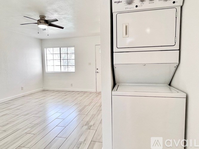A white washing machine is in a room with a fan and a window.