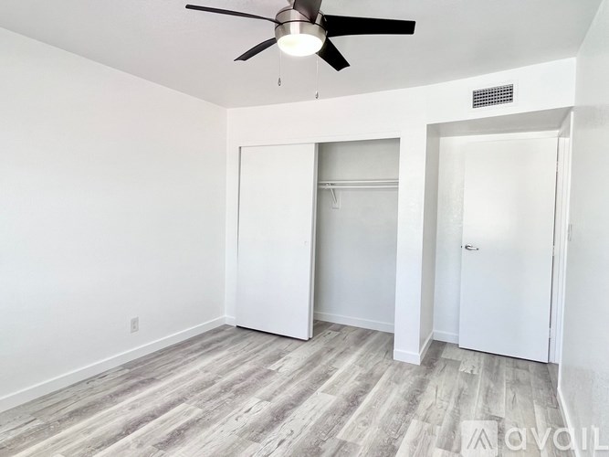 A room with a ceiling fan and two doors.