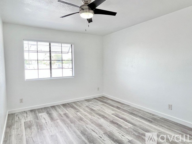 A room with a ceiling fan and a window with blinds.
