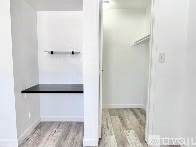 A room with a black shelf and wooden flooring.