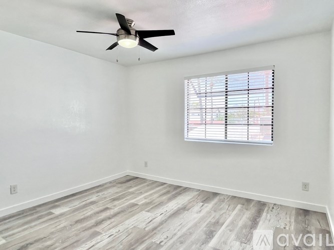A room with a ceiling fan and a window with blinds.